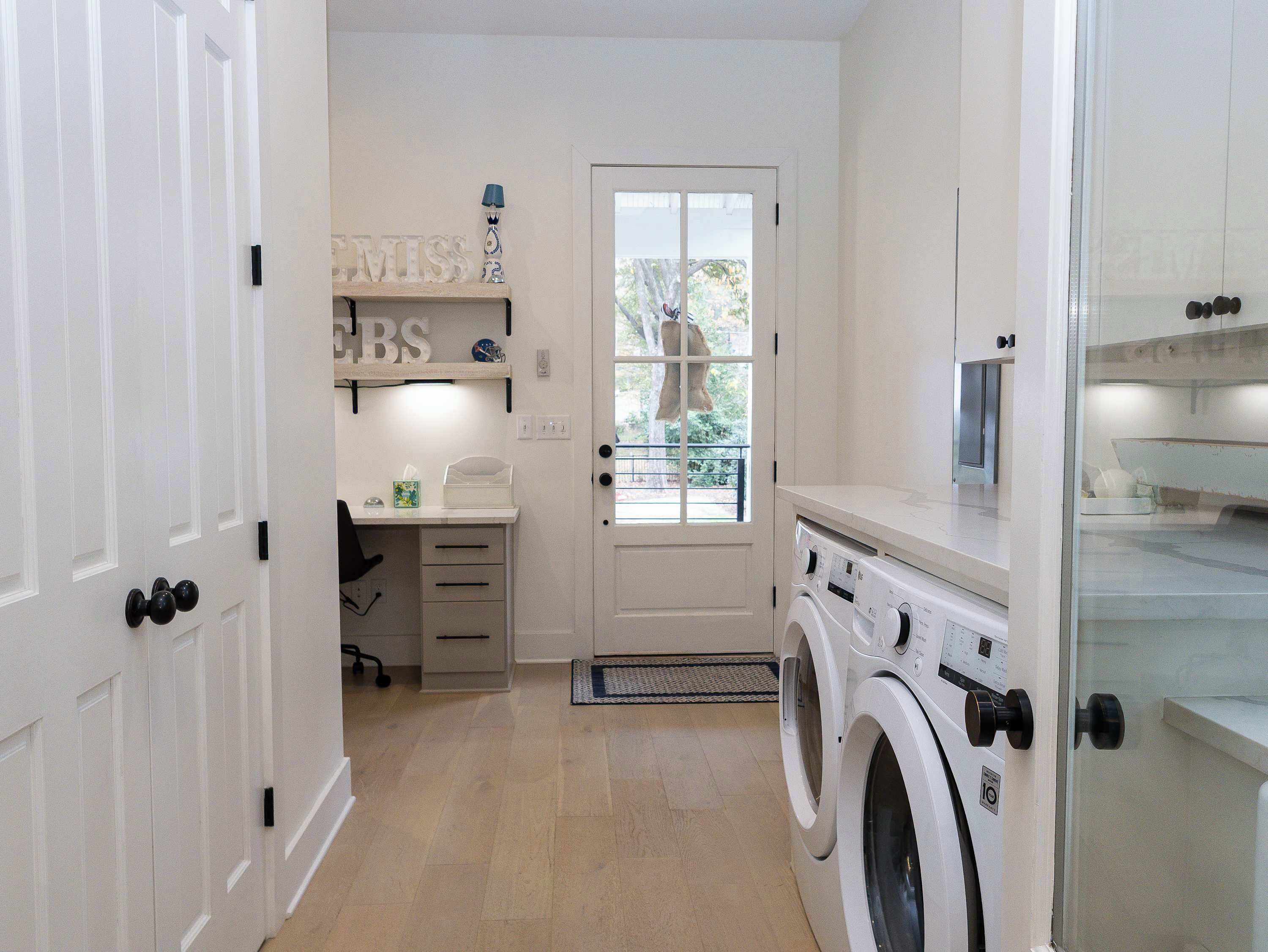 Une buanderie équipée d’un lave-linge, d’un bureau avec une chaise et d’une fenêtre donnant sur des arbres.