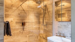 A modern bathroom with a glass-enclosed shower, a white sink, and a mirror above the sink.