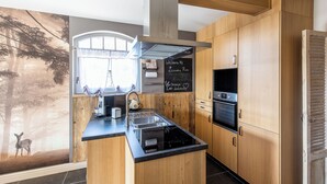 A modern kitchen with wooden cabinets, a central island, and a chalkboard with a welcome message.