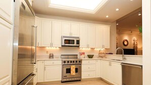A modern kitchen with white cabinets, stainless steel appliances, and a skylight.