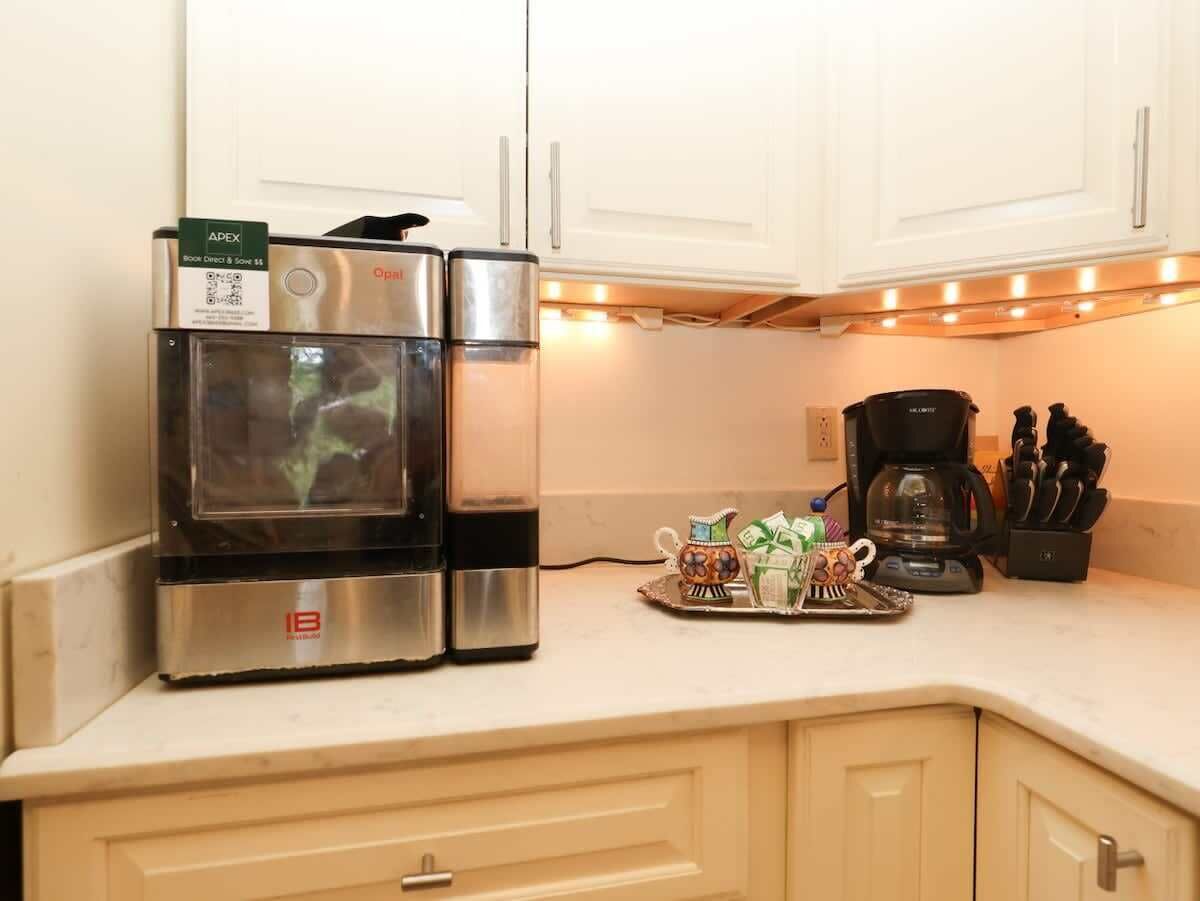 A kitchen with stainless steel appliances, a coffee maker, and a tray with gifts.