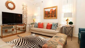 A living room with a sofa, a television, a zebra rug, and a painting on the wall.