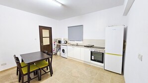 Uma cozinha compacta com mesa de jantar, cadeiras, máquina de lavar, micro-ondas, fogão e frigorífico.
