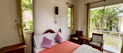 A bedroom with a bed, two nightstands, a wooden bench, and a window with curtains.