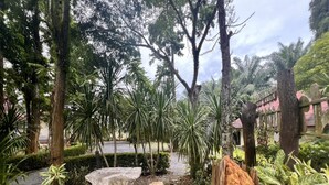 A garden with stone benches, a wooden fence, and various plants. - OYO 75517 Mananchaya Resort (Ao Luek)