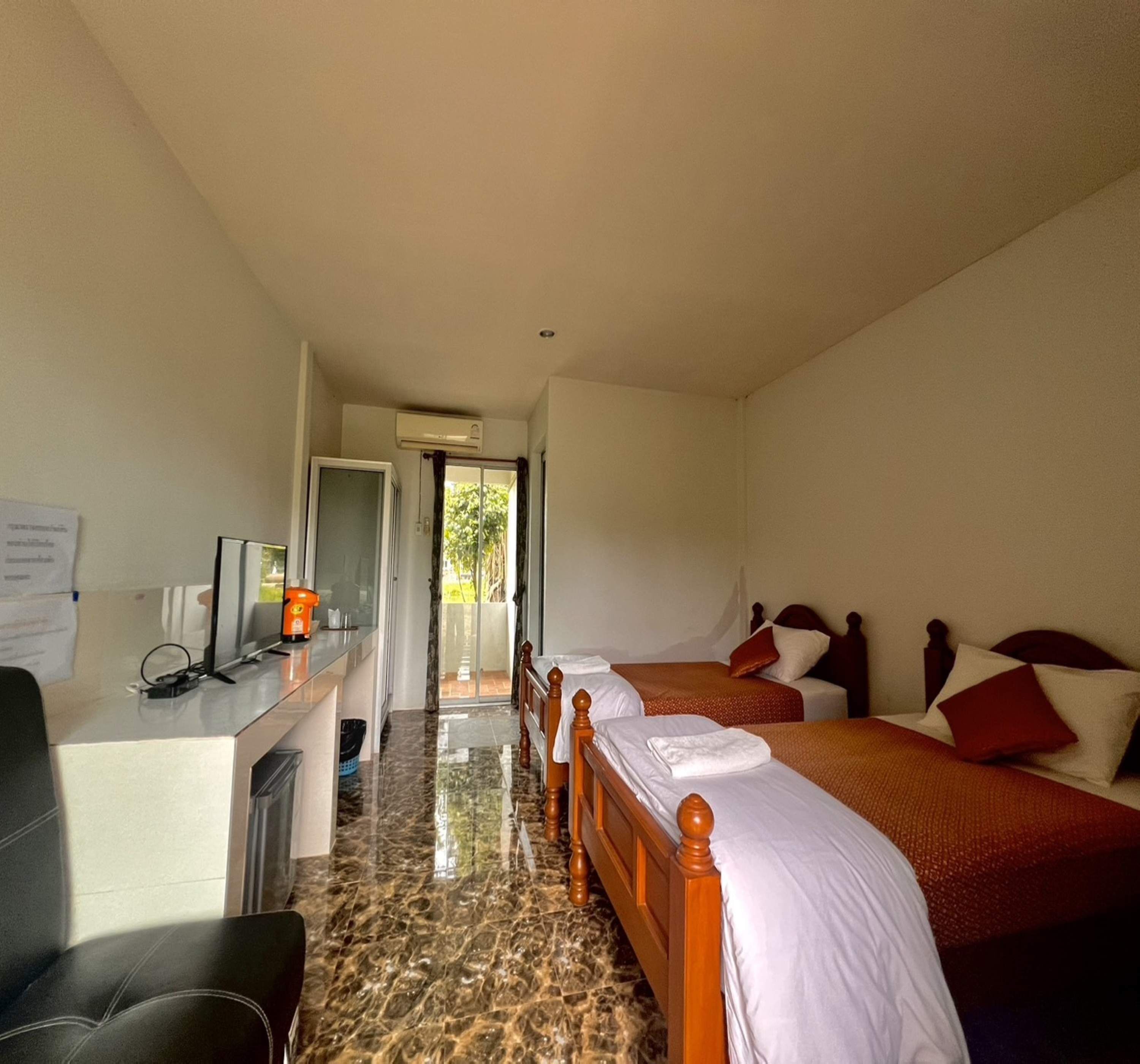 A hotel room with a desk, two beds, a TV, and a bathroom.