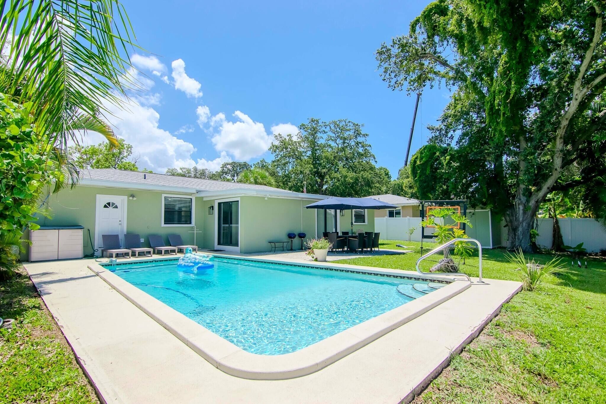 Piscina com uma casa ao fundo, em meio ao verde.