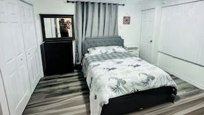A bedroom with a bed, a dresser, a mirror, and a door. - Cozy 2 Bedroom Apartment near St.John's airport with lockbox key Entrance. (St. John's)