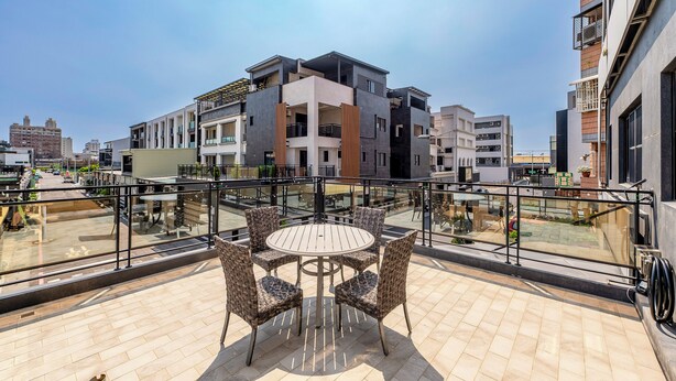 Eine Dachterrasse mit einem runden Tisch und Stühlen, umgeben von einem Glasgeländer.