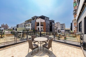 Eine Dachterrasse mit einem runden Tisch und Stühlen, umgeben von einem Glasgeländer.