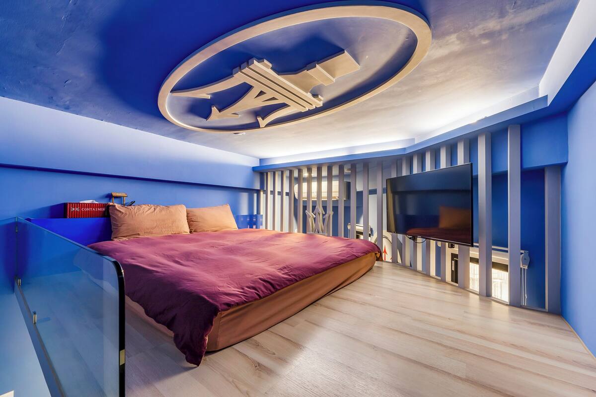 Ein modernes Schlafzimmer mit einem großen Bett, einem Fernseher und einem besonderen Deckengestalt.