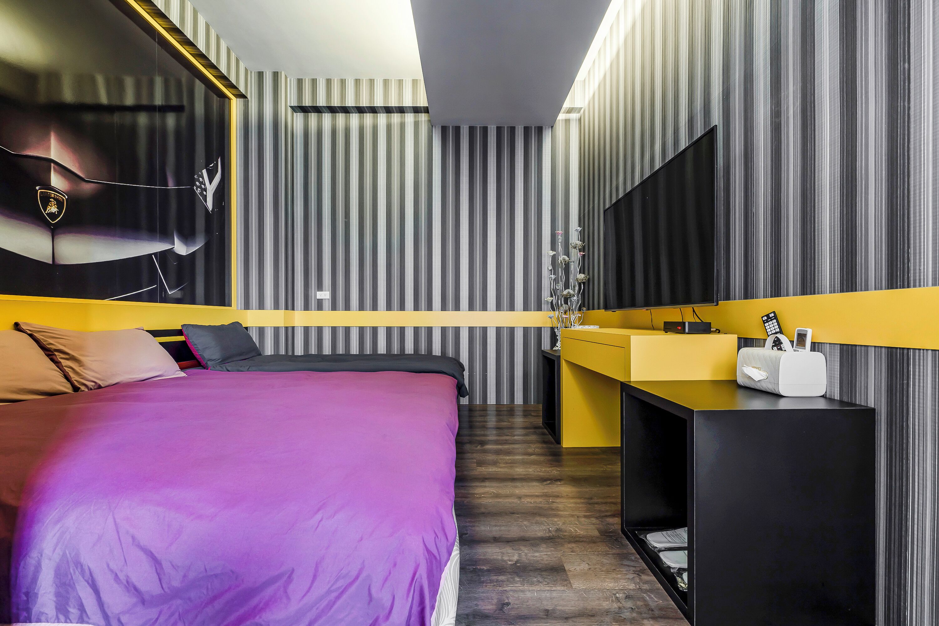 Una habitación de hotel moderna con una cama grande, una mesita de noche, un espejo y un televisor montado en la pared.