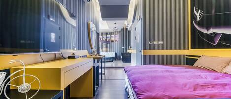 Una habitación de hotel moderna con una cama grande, un escritorio y un espejo.