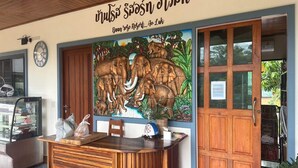 A reception desk with a wooden finish, a clock, and a mural of elephants on the wall. - Capital O 75518 Baan Rose Resort Ao Luk (Ao Luek)