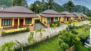 A row of yellow buildings with tiled roofs, surrounded by lush greenery and mountains. - Capital O 75518 Baan Rose Resort Ao Luk (Ao Luek)