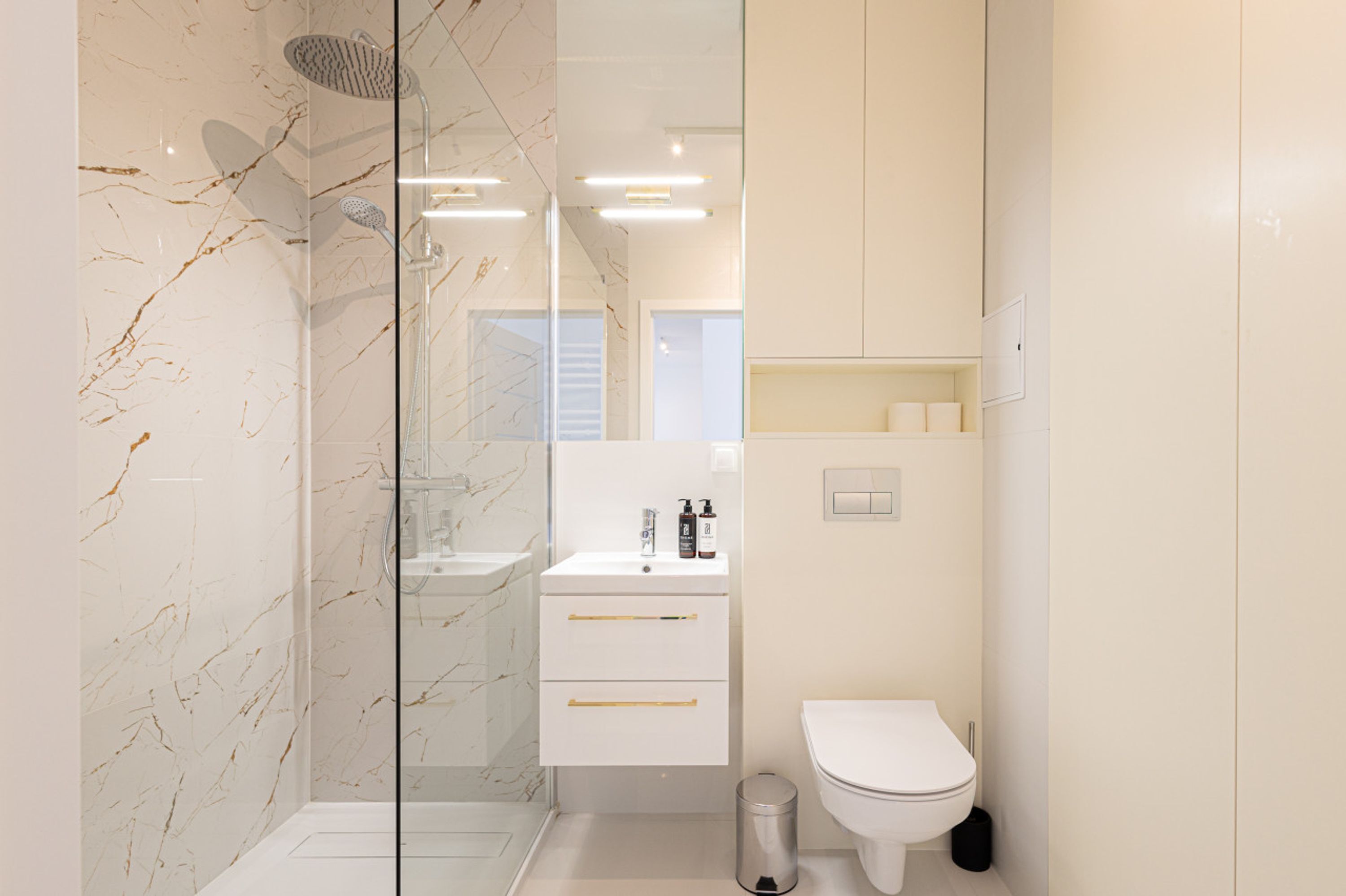 A modern bathroom with a glass-enclosed shower, a white sink, and a toilet.
