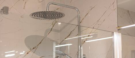 A modern shower with a handheld showerhead and a wall-mounted rain showerhead.