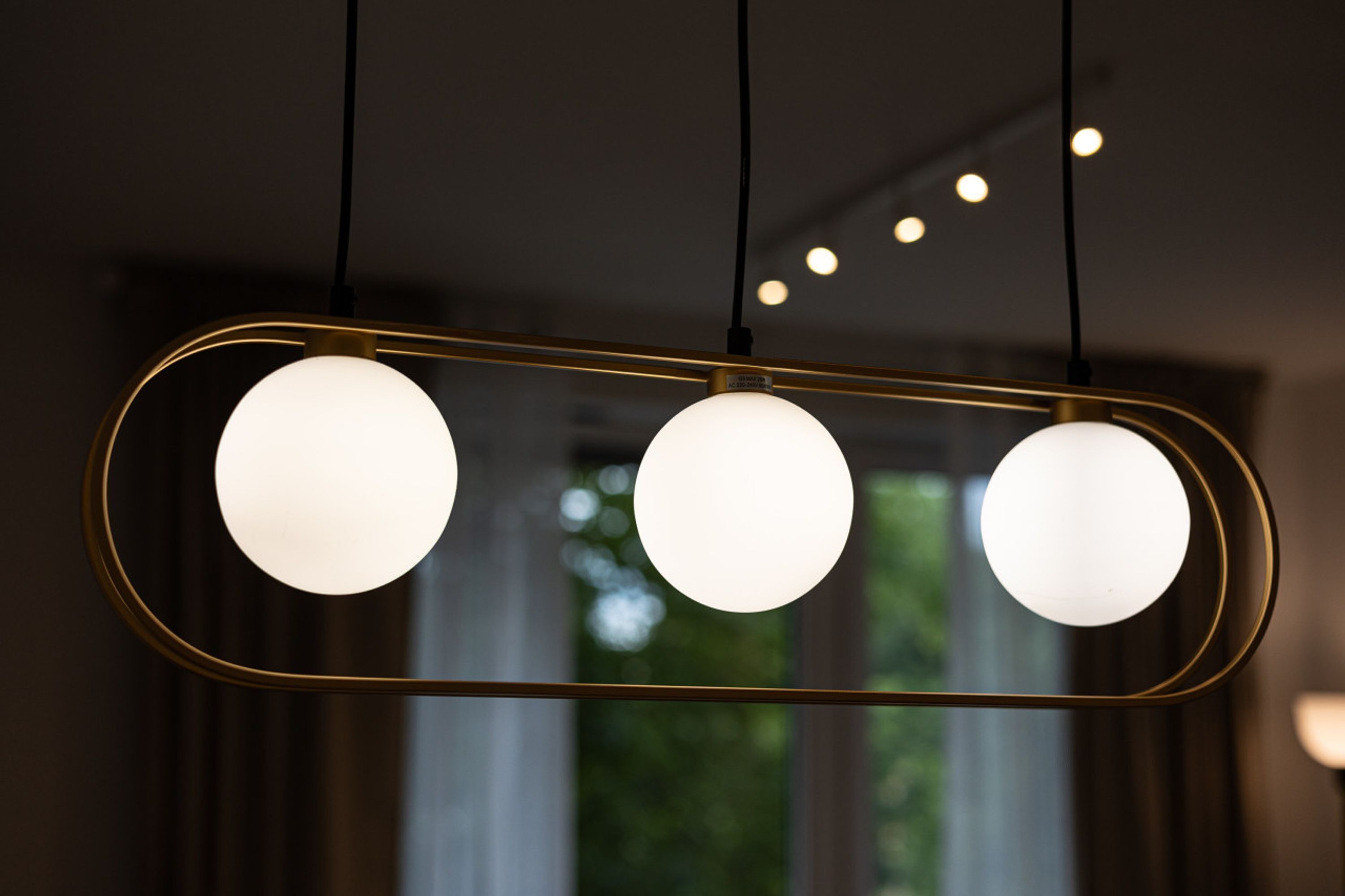 Un candelabro moderno con tres luces esféricas en un marco rectangular.