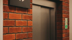 Un mur de briques avec une porte et une enseigne portant un symbole.