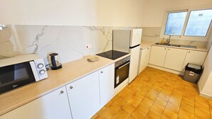 A compact kitchen with a microwave, kettle, stove, oven, and a small sink. - Downtown Rooms, 200m from Marina Beach (Larnaca)