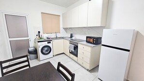 A compact kitchen with a washing machine, oven, microwave, and refrigerator. - Downtown Rooms, 200m from Marina Beach (Larnaca)