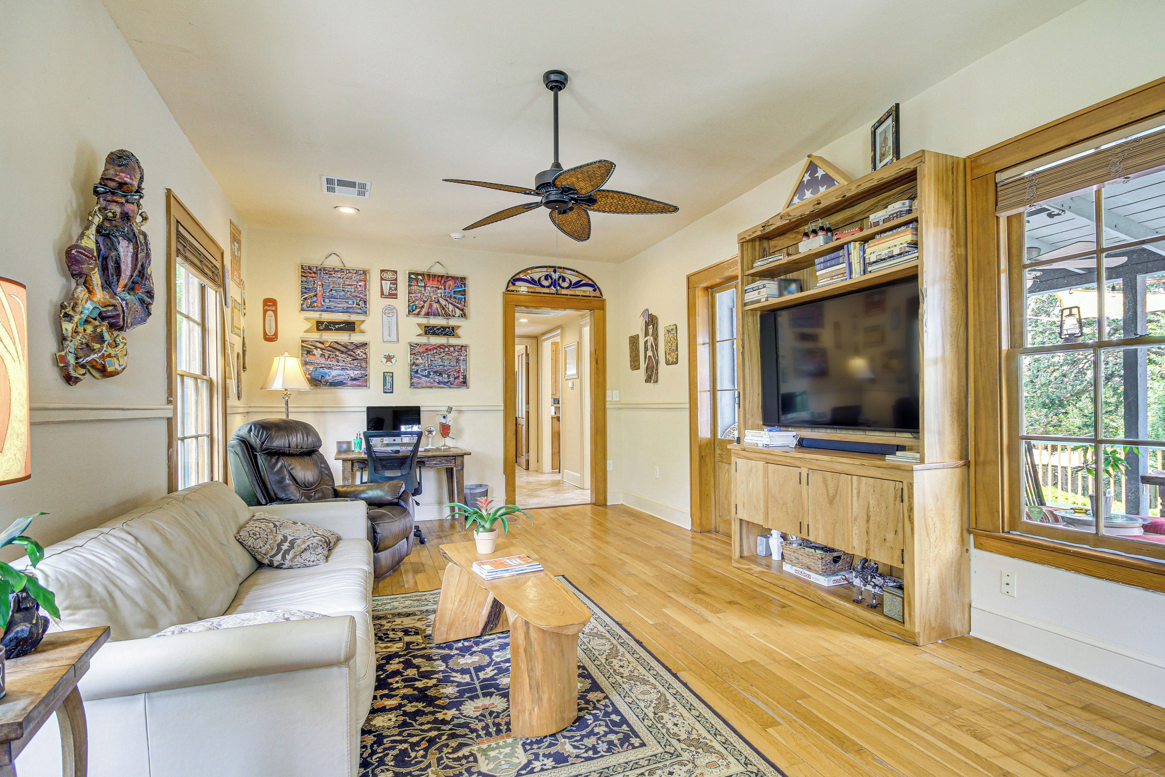 A spacious living room with a ceiling fan, a large TV, and a wooden cabinet.