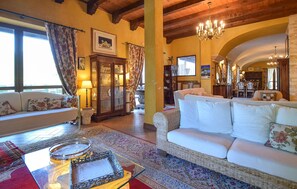 A spacious living room with a high ceiling, a fireplace, and a dining area with a chandelier. - 4 bedroom cozy home in Lucera (Lucera)