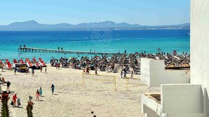 A beach with a volleyball court, umbrellas, and a pier extending into the sea. - Beachfront · Terrace · Adults Only (Alcudia - Puerto de Alcudia)