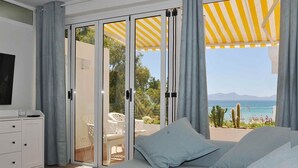 A bedroom with a large bed, a TV, and a view of the sea. - Beachfront · Terrace · Adults Only (Alcudia - Puerto de Alcudia)