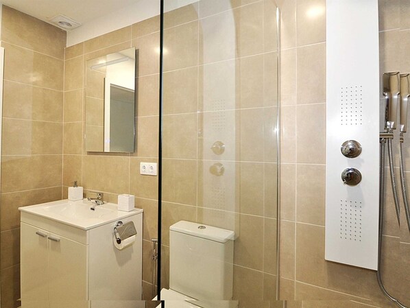 A modern bathroom with a glass-enclosed shower, a white sink, and a toilet.