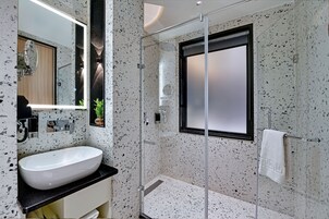 A modern bathroom with a freestanding sink, a glass shower enclosure, and a large mirror.