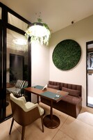 Een moderne woonkamer met een bruine bank, een houten salontafel en een groene fauteuil. Er is een ronde groene wanddecoratie en een hanglamp.