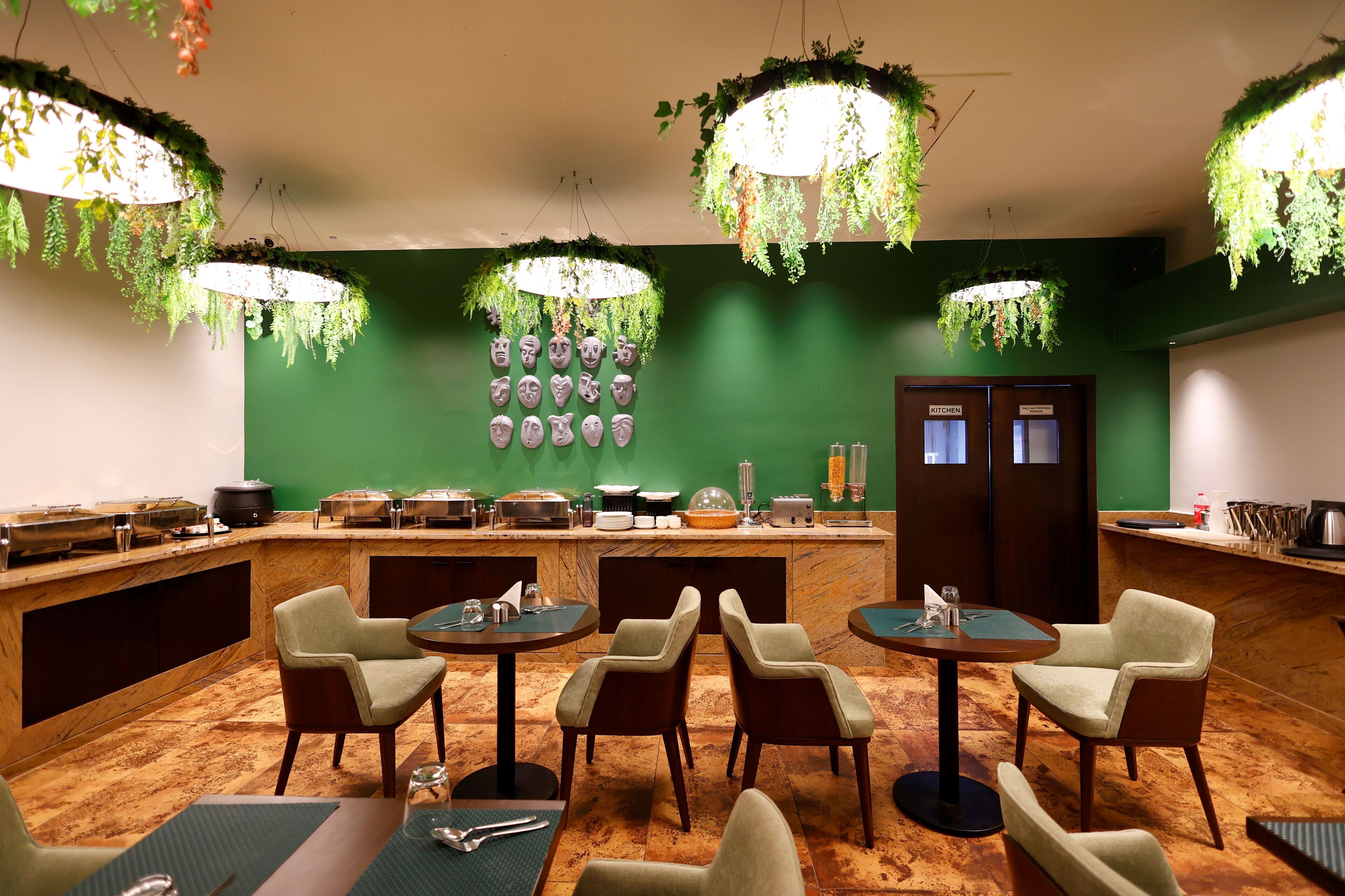 Un restaurante con una pared verde, plantas colgantes y una zona de bufé.