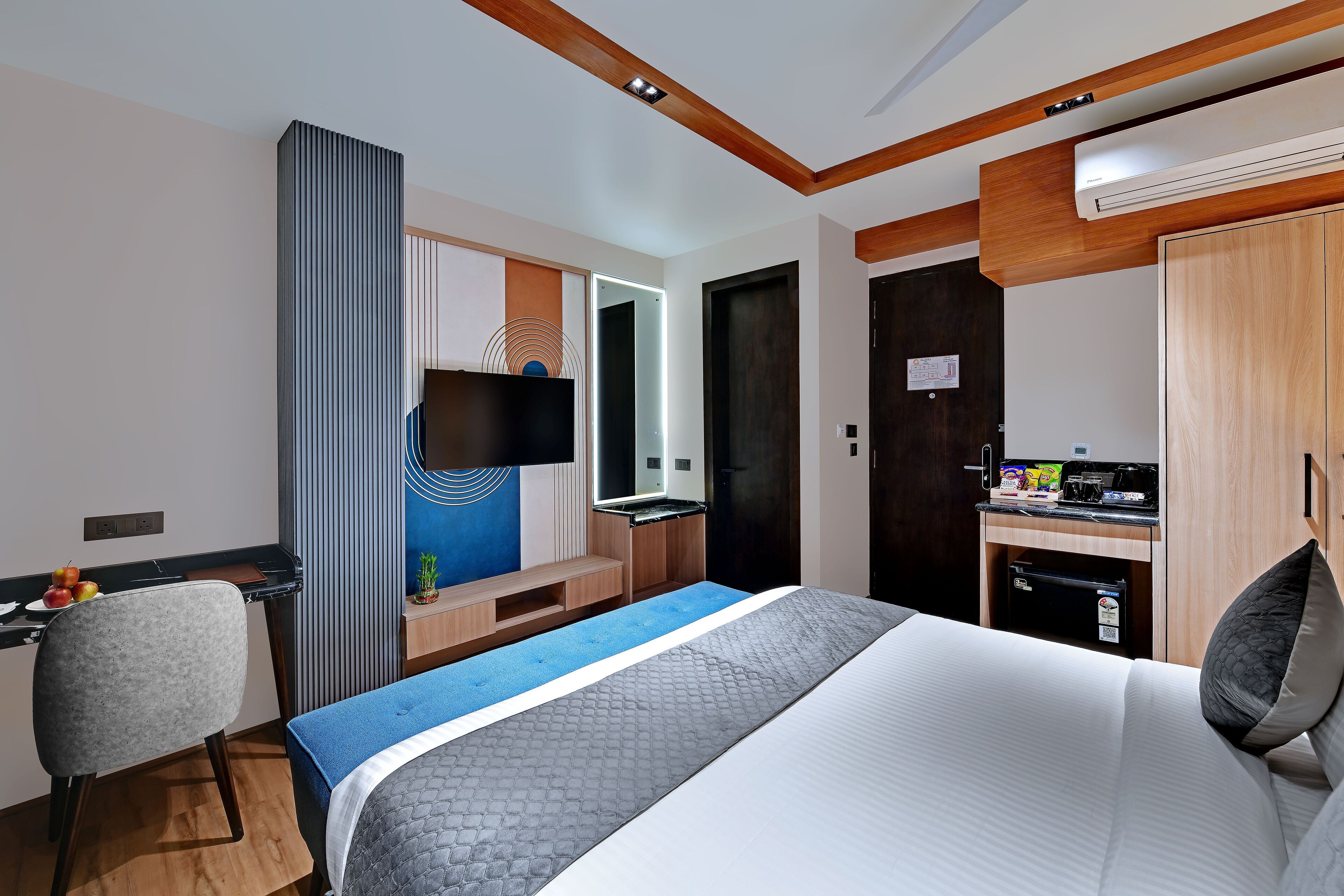 Ein Hotelzimmer mit Bett, Schreibtisch, Stuhl, Fernseher und einer Küchenzeile.