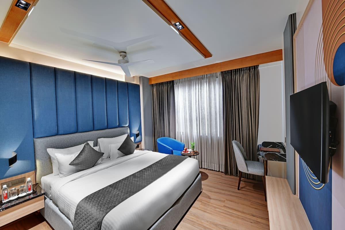 Ein modernes Hotelzimmer mit einem großen Bett, einem Schreibtisch, einem Stuhl und einem Fernseher.
