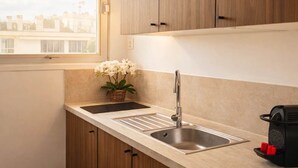 Een moderne keuken met houten kastjes, een dubbele spoelbak en een raam met uitzicht op gebouwen.