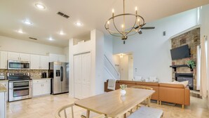 A modern kitchen with white cabinets, stainless steel appliances, and a wooden dining table with benches. - Private Beach at Lakefront Summerfield Getaway! (Summerfield)