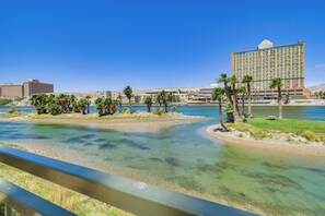 Een hotel met een groot gebouw, een rivier en palmbomen.