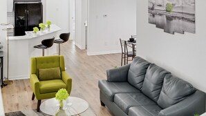 A modern living room with a grey leather sofa, a green armchair, and a glass coffee table. - Tasteful 3BR I Free Parking I Workspace (Grand Prairie)