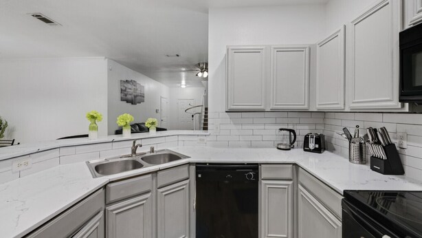 A modern kitchen with white cabinetry, a dishwasher, a stove, and a microwave. - Tasteful 3BR I Free Parking I Workspace (Grand Prairie)