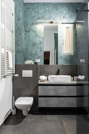 A modern bathroom with a white toilet, a sink with a large mirror, and a shower area.