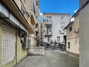 A narrow alleyway between buildings with balconies, air conditioning units, and a visible storefront.
