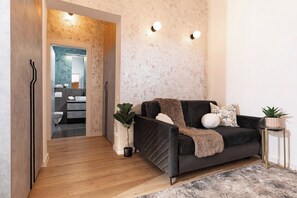 A modern living room with a dark sofa, a small side table, and a potted plant.