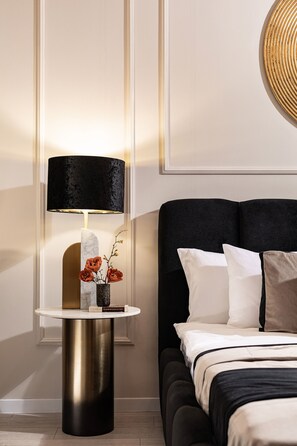 A modern bedroom with a bed, a bedside table with a lamp, and a vase with flowers.