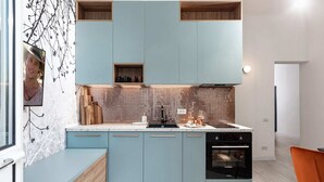 A modern kitchen with light blue cabinets, a tiled backsplash, and a built-in oven. - Qult·co - Legends of the Fall (București)