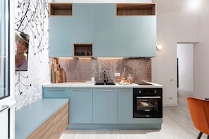 A modern kitchen with light blue cabinets, a tiled backsplash, and a built-in oven. - Qult·co - Legends of the Fall (București)