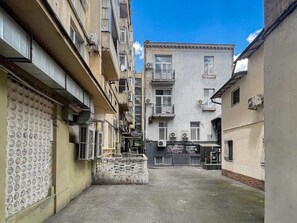 A narrow urban alleyway with multi-story buildings, air conditioning units, and a PS Gaming store.