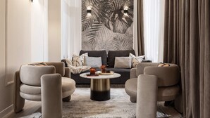A modern living room with a sofa, two armchairs, a coffee table, and a large wall art piece. - Qult·co - Legends of the Fall (București)