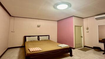 Une petite chambre à coucher, bien rangée, avec un lit simple, une porte et un appareil de climatisation.
