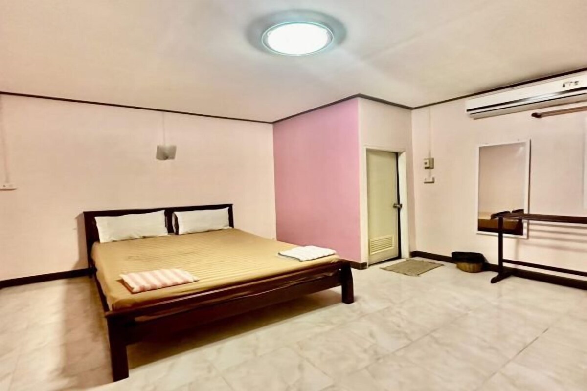 A bedroom with a bed, a door, a mirror, and a ceiling light.